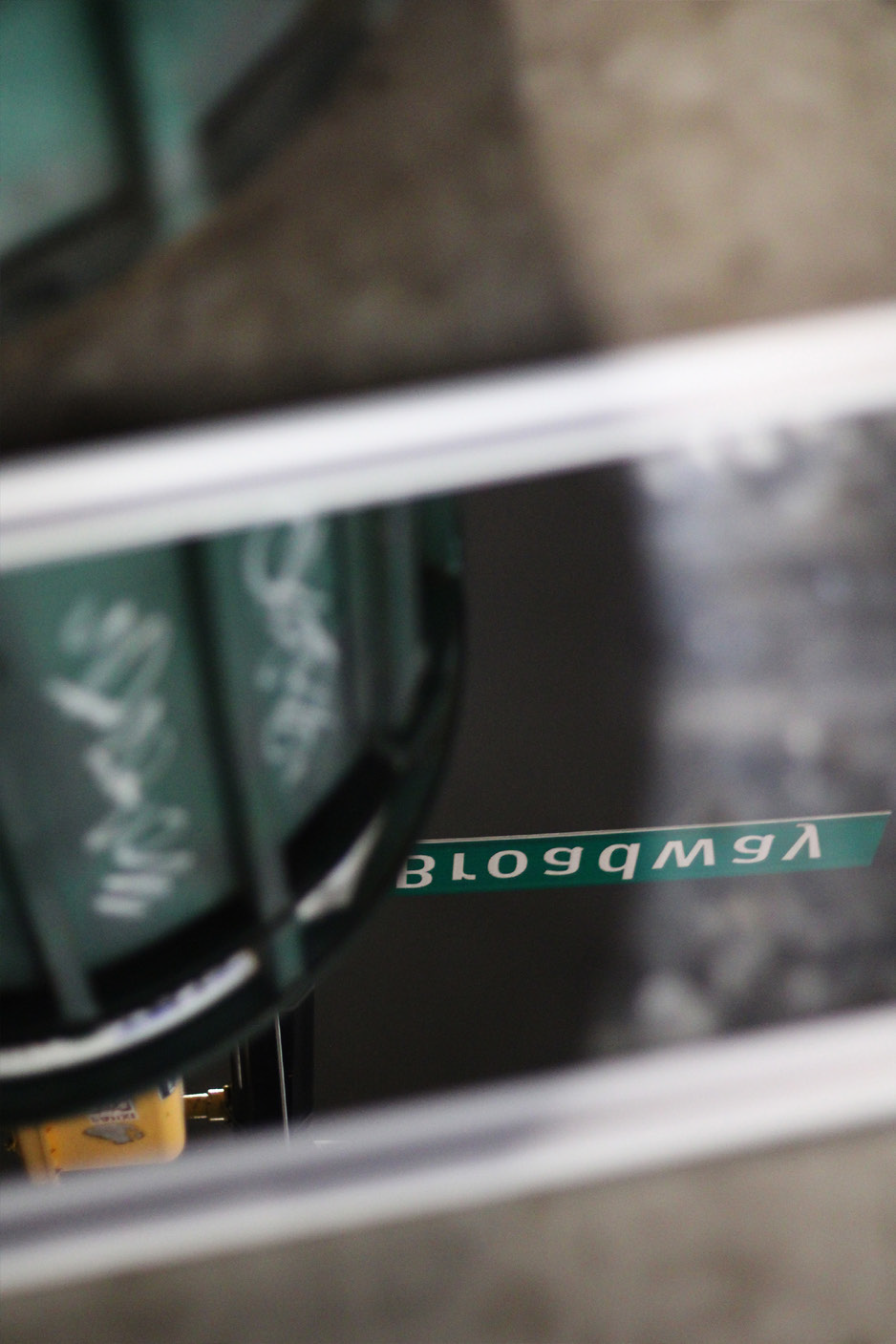 the inverted reflection of a green New York City Broadway sign.