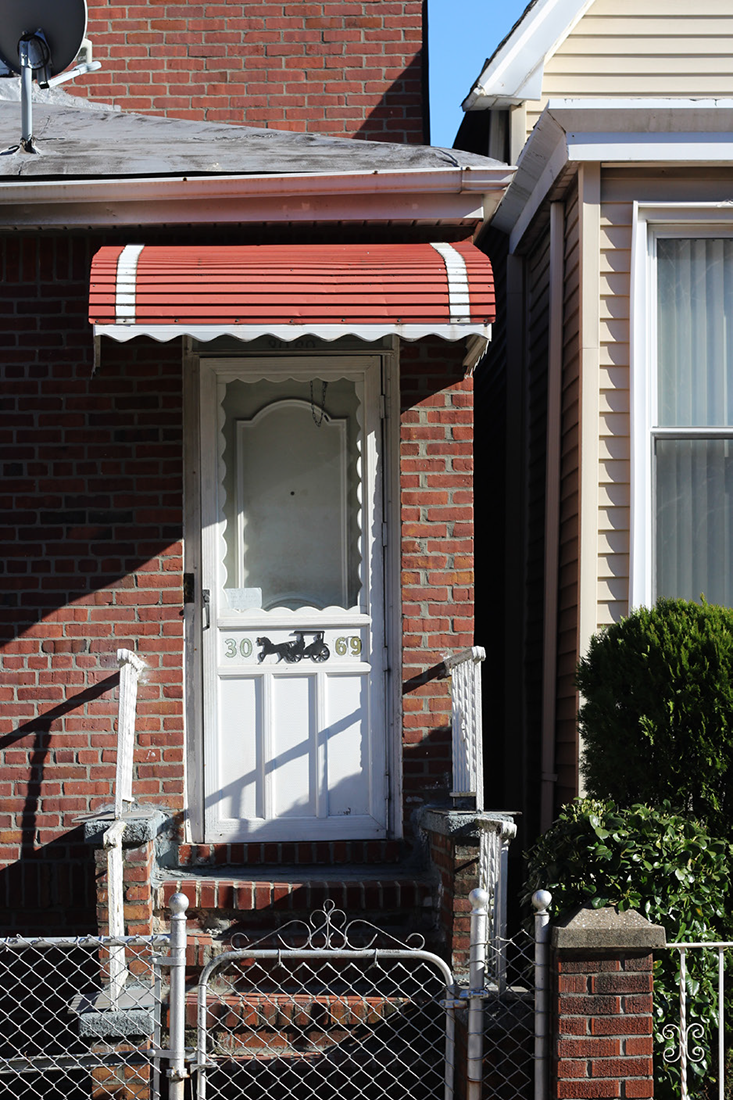 a red awning and white door of a single family home numbered 30-69.